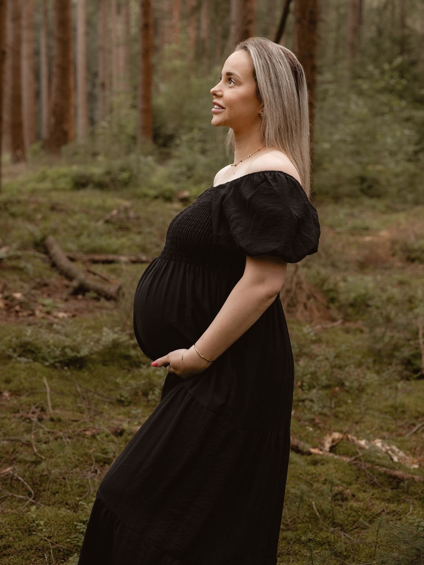 Zwangere vrouw houdt haar buik vast in het bos